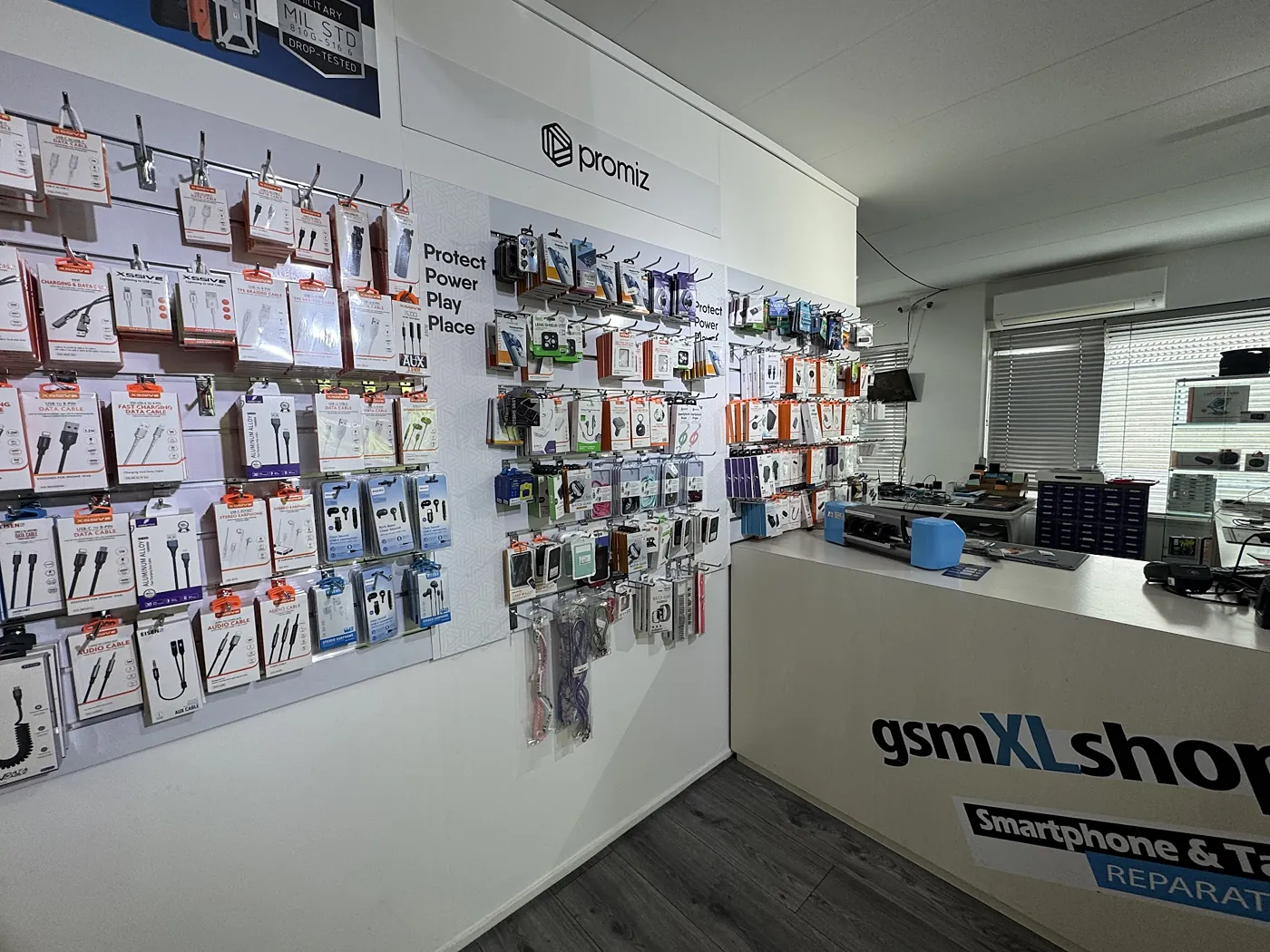 De wand met hoesjes, kabels en opladers in de winkel
